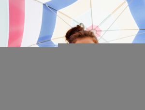 Woman in sunglasses holding beach umbrella