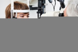 Smiling boy getting visual field test done by the optometrist